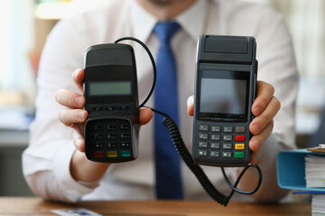 Businessman holding different pos terminals in his hands closeup. Sales of machinery concept