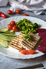 Continental preparation of cottage cheese grilled with boiled vegetables on a plate. Close up.