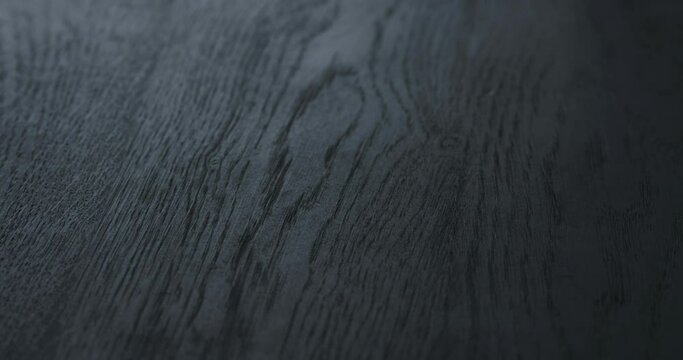 Slow motion handheld shot of black painted oak surface