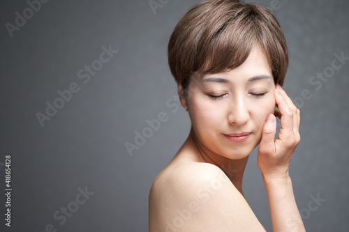 頬に手を当てて目をつぶる中年の日本人女性 Wall Mural Mapo