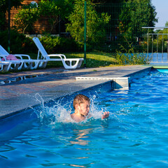 The boy jumps into the pool, children's games and entertainment in the aqua park.