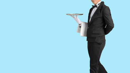 Handsome waiter in tuxedo and gloves holding empty tray and napkin whit Dicut part