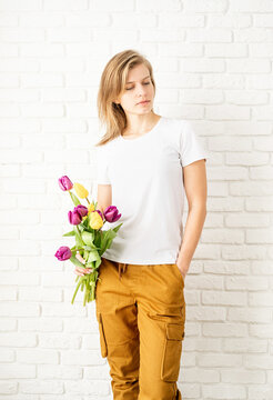 Young woman wearing blank white t-shirt holding tulips flowers