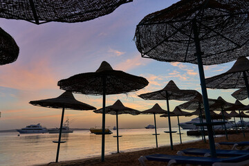Beautiful sunrise at sea with beach and yachts