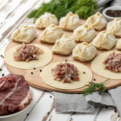 Raw meat filling on rolling dough circles on wooden board. Process of cooking dumplings. Ingredients to create culinary masterpiece. Meal or food preparation of Convenient food. Square format or 1x1.