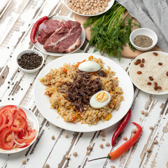 Simple Rustic food plate. Rice with meat, tomato salad and hot chili pepper on wooden kitchen table. Ingredients for creating delicious pilaf. Tasty dinner. Square format for social media. Top view.