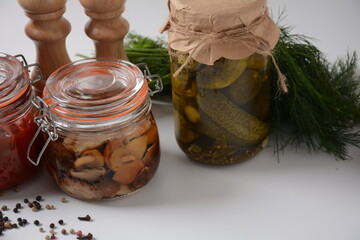 Jars of Homemade pickled vegetables: cucumbers, tomatoes, honey agarics mushrooms, on white  background. Marinated and Fermented food. Fermented preserved vegetarian food concept.