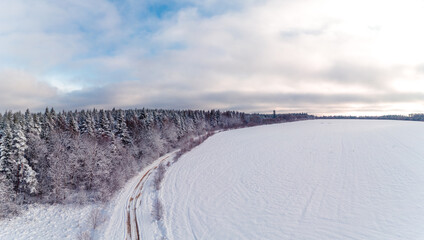 Snow-covered field and forest, panorama of winter landscape.