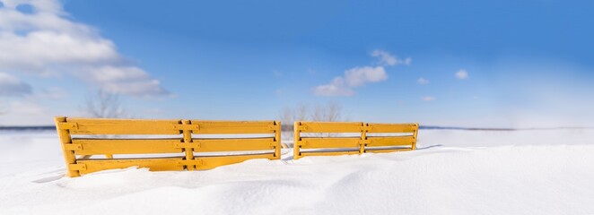 Vintage wooden Bench Painted yellow, rungs snow covered and in deep snow. Copyspace for Street Billboard placards texture background.