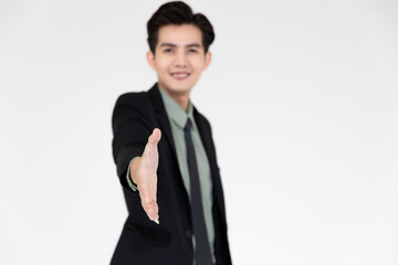 Portrait of young and handsome Asian businessman in a black suit pose with smile face and giving hand for shake with self-confidence to camera isolated on white background