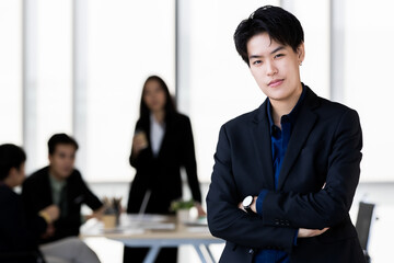 A tomboy woman in casual suit standing with self-confident in office and colleagues in background. Transgender in modern business workplace concept