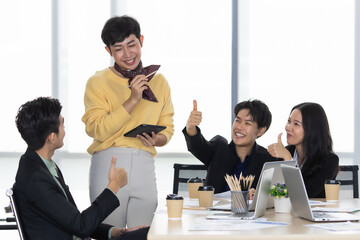 A group of multi sex colleagues, tomboy, transgender and lesbian businesspeople working together with happy and intimate manner. The sissy gay presenting work with cheerful and funny