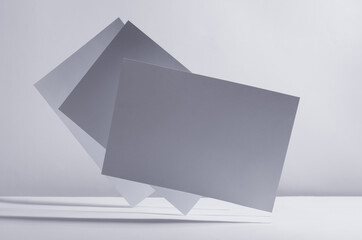 Modern simple geometric white grey abstract background with flying blank rectangle papers in light with shadow.