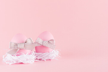 Simplicity purity easter background - pink eggs with  grey bows in white nest on pastel pink color.