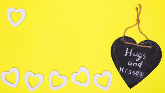 Dancing white hearts, next to a large one with an inscription hugs and kisses. Animated, abstract background with copy space. Postcard for Valentine's day, wedding, congratulations to lovers.