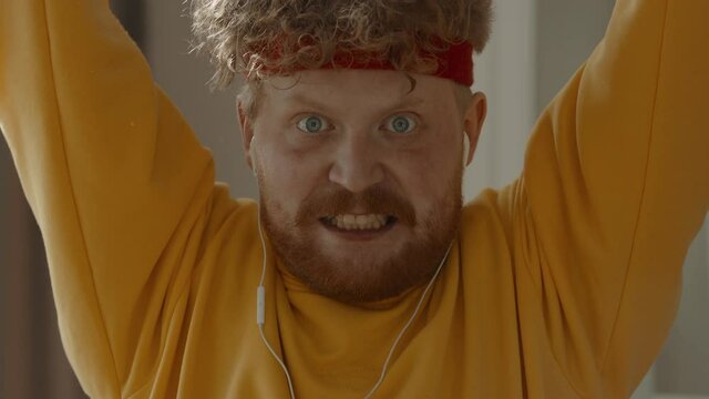 CARSH ZOOM Portrait of funny overweight Caucasian man working out with dumbbells at home, looking into camera. Bright, commercial high key advertising style lighting