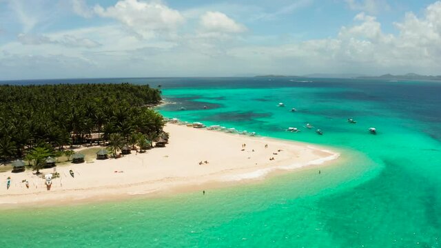 Tropical island in the ocean with palm trees on white sand beach. Daco island, Philippines. Summer and travel vacation concept