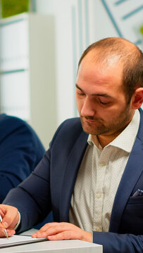 Businessman reading paper document, discussing contract with confident partner, signing investment papers. Executive director meeting shareholders in start up office, making satisfactorily agreement.