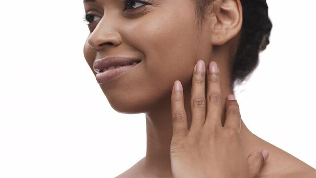 Tracking shot of young african american woman stroking her face and shoulder skin, enjoying smoothness