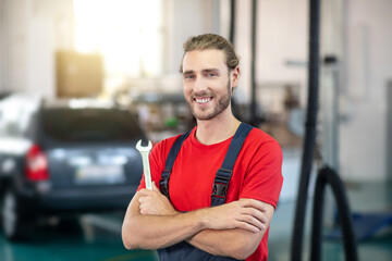 Joyful man motor mechanic standing in workshop