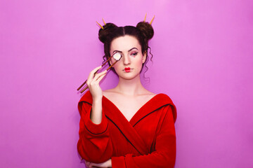 Beautiful young girl in the image of a Japanese woman holding a roll with chopsticks for sushi