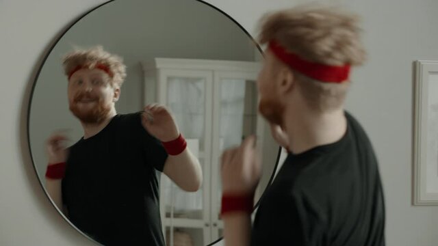 CRASH ZOOM Portrait of funny Caucasian man dancing in front of the mirror after working out, cheering himself. Motivation, self confidence concept