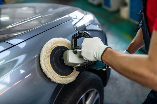 Male hands with polishing machine on surface of car