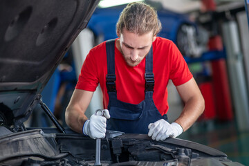 Concentrated repairman working in hood of car