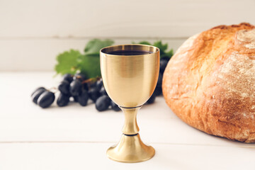 Chalice of wine with bread on white wooden background