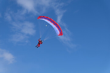 Skydiving. A skydiver is flying a parachute in the blue sky.
