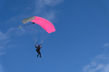 Skydiving. A skydiver is flying a parachute in the blue sky.