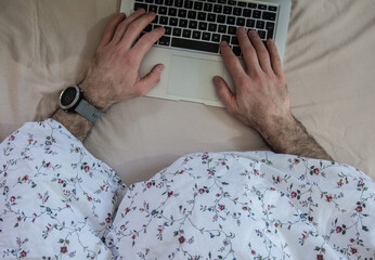 Man in bed with laptop using internet in online service