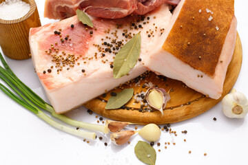 raw pork meat and lard with salt, spices and garlic on a cutting board, white background