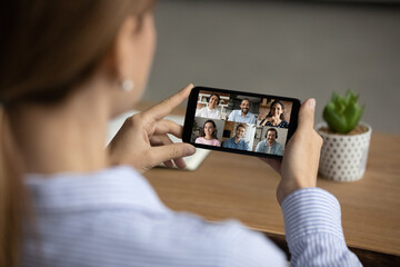 Close up back view of woman have webcam online team meeting with diverse colleagues on smartphone....