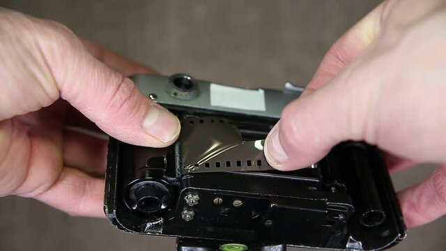 A man inserts a film into the camera.