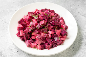 Traditional Scandinavian beetroot and apple salad with mayonnaise, sour cream and balsamic vinegar. Pickled beets with apples in a white plate on a light gray table