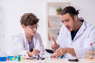 Obraz premium Young father and son chemists in the lab