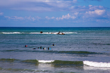 Tel Aviv, Israel - March 04, 2021: People surfing, surfers swimming in cold water and waiting sea wave on surfboard. Aquatic sport hobby, healthy lifestyle. Mediterranean Sea coast.