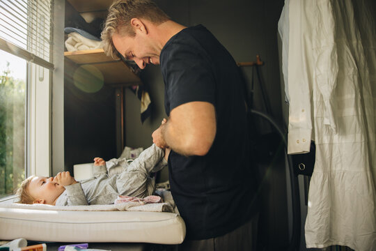 Man changing clothes of his toddler at home