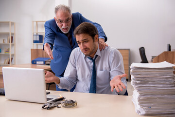 Obraz premium Young male employee and old boss burning papers at workplace