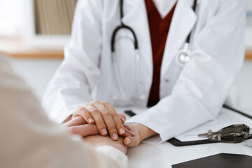 Hands of unknown woman-doctor reassuring her female patient, close-up. Medicine concept