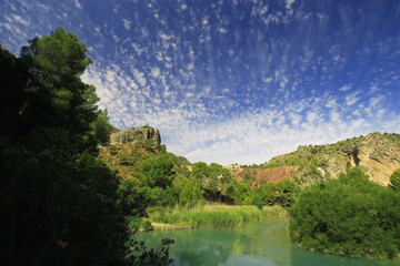 Fototapeta na wymiar Río Segura aguas abajo del embalse del Cenajo, en Moratalla (Murcia), con cielo con nubes medias (altocúmulos), un día de verano.