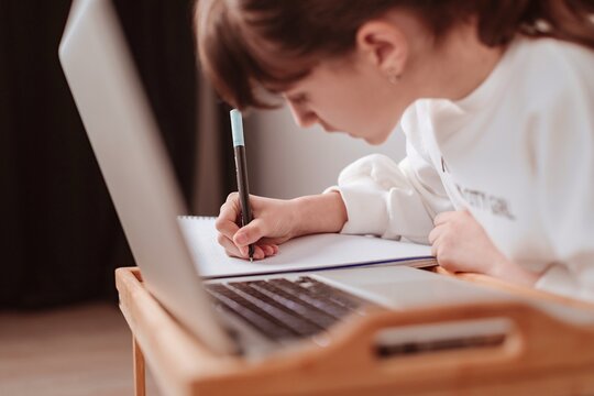 Ni&ntilde;a haciendo deberes con un ordenador port&aacute;til