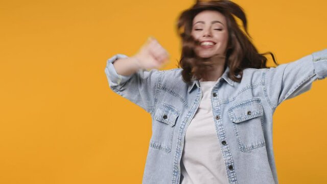 Cheerful funny young woman 20s in denim jacket white t-shirt isolated on yellow background studio. People lifestyle concept. Doing dab hip hop dance hands move gesture youth sign hiding covering face