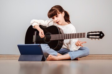 Niña tomando clases de guitarra online por la tablet