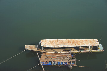 The old boat floating next to the river bank - 418678900