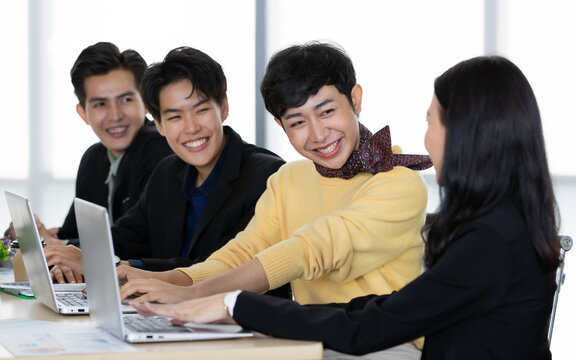 A group of multi-sex colleagues businesspeople, tomboy and transgender gay, working together with happy and intimate manner with laptop notebook computer in office
