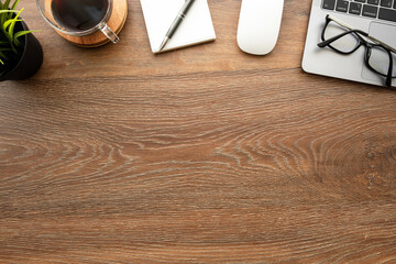 Wood office desk table with laptop computer, cup of coffee and office supplies and tools. Top view with copy space, flat lay.