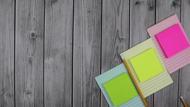 Colorful blank memo pads with matching notebooks and copyspace on a rustic wood background viewed top down in a flat lay still life. Stop motion
