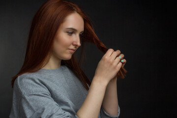 Obraz premium Red-haired young girl on black background in a gray T-shirt